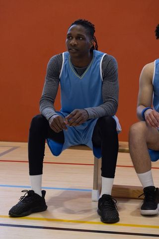 Diverse Basketball Team Sitting in Gym, Preparing for Match