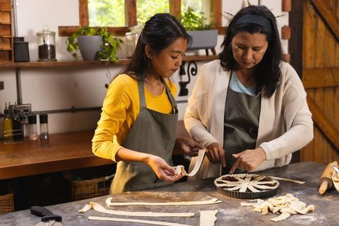 Mother and daughter crafting lattice pie top in farmhouse kitchen