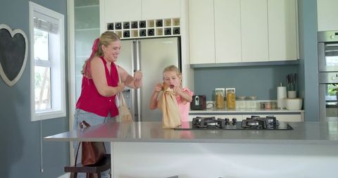 Mother and daughter preparing lunch on kitchen island with gas cooktop, family bonding