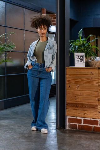 African american woman standing in industrial cafe lobby with qr code and plants