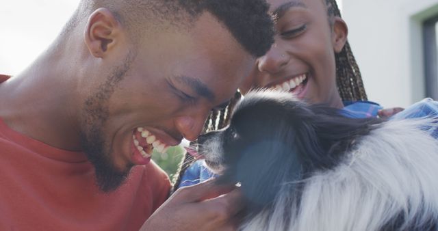 Close-up of a cheerful couple interacting with their pet dog in an outdoor setting. Displays emotions of joy and intimacy. Ideal for use in pet care promotions, family and relationship services, or advertisements highlighting companionship with pets.
