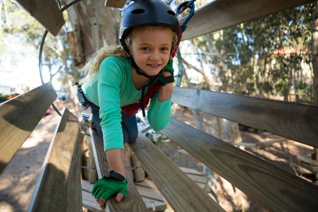 Little girl wearing helmet trying to cross obstacle in the forest
