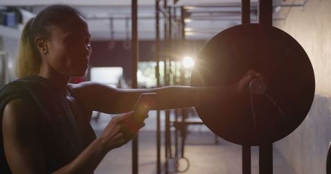 Focused Woman at Gym Leaning on Barbell, Checking Smartphone