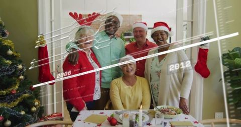 Senior friends celebrating christmas dinner together at cozy decorated home dining table