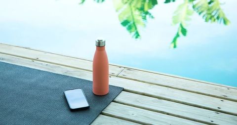Coral Bottle with Phone on Poolside Deck at Yoga Session