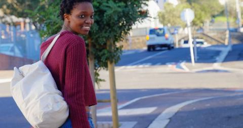 Happy young woman with backpack walking in urban street
