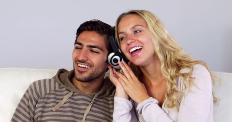 Happy Couple Enjoying Music Together at Home on Cozy Couch