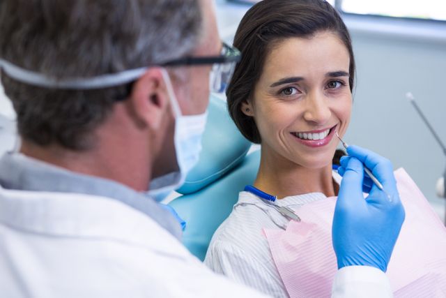 Woman smiling while receiving dental treatment at a clinic. Ideal for use in healthcare, dental care, and medical service promotions. Can be used in advertisements for dental clinics, oral health awareness campaigns, and patient care brochures.