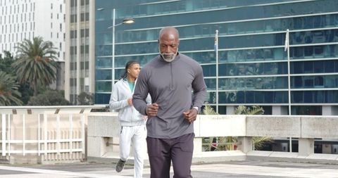 Senior African American Man Jogging with Younger Male Companion on Urban Promenade