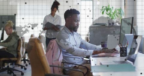 Focused african american man working in modern office with world map overlay