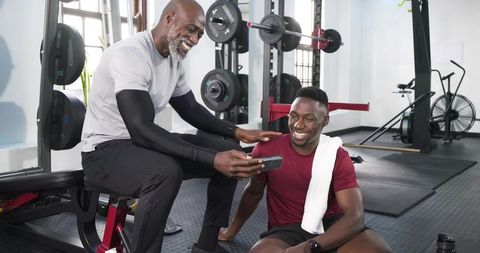 Smiling trainer and client discuss workout progress at gym