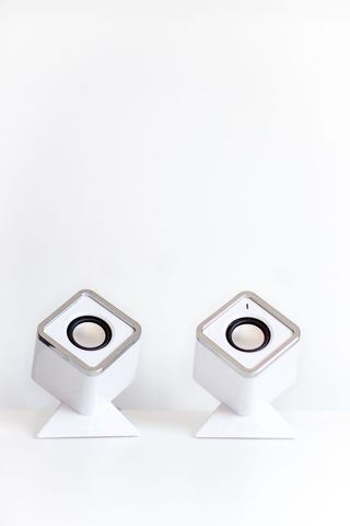 Pair of minimalist white desktop speakers on stands with clean copy space for ads