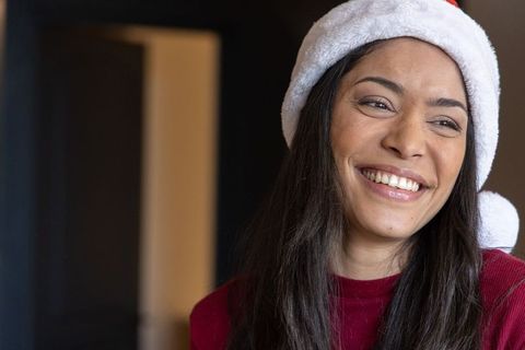 Young woman wearing santa hat laughing at home during cozy christmas celebration