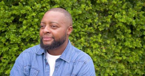 African american man wearing denim shirt in garden looking relaxed lifestyle natural portrait