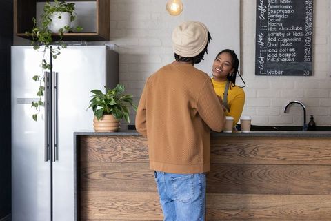 African american barista serving takeaway coffee to customer at cozy modern cafe counter