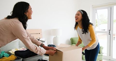 Women preparing for a trip packing suitcase and sealing box