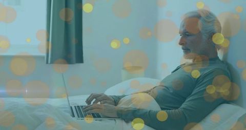 Senior Man Relaxing in Bed with Laptop Experiencing Modern Comfort at Home