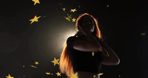 Backlit woman in crop top with gold star confetti: