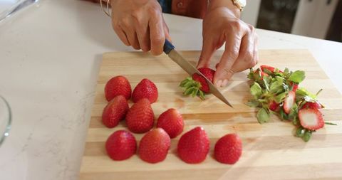 African american woman preparing strawberries on wooden cutting board closeup home cooking