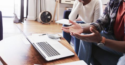 Couple Discussing Finances with Laptop and Calculator at Home