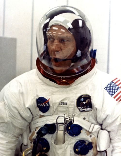 Apollo 11 astronaut Edwin E. Aldrin Jr. is in a spacesuit, looking relaxed during suiting operations at Kennedy Space Center’s Manned Spacecraft Operations Building. This image captures a historic moment before the first manned lunar landing mission in 1969. Ideal for articles or exhibitions on space exploration history, NASA missions, or astronaut training.