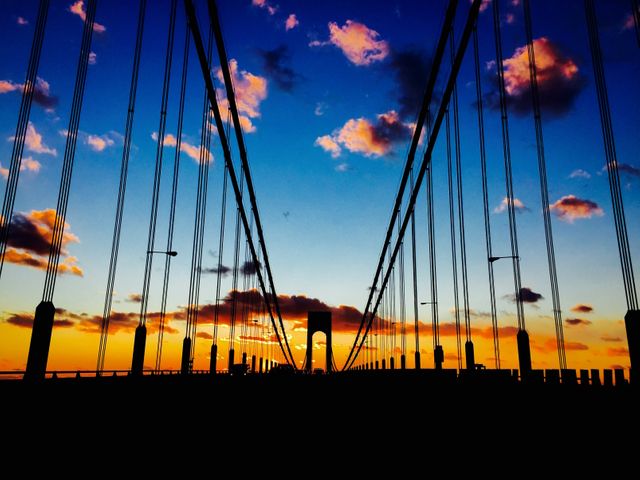 Silhouette of Suspended Bridge at Sunset with Vibrant Sky and Clouds - Download Free Stock Photos Pikwizard.com