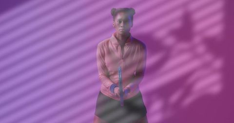 Holding training rod, woman posing with determined gaze on purple background with striped shadows