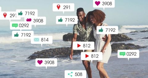 Happy couple walking on beach surrounded by social media icons