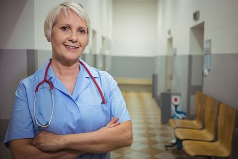 Experienced female nurse in hospital corridor with stethoscope