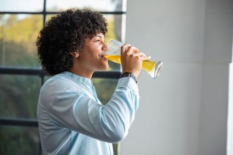 Young African American Man Enjoying Fresh Juice by Window
