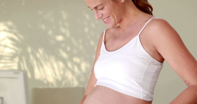 Smiling caucasian pregnant woman looking at her belly at home, copy space - Download Free Stock Photos Pikwizard.com