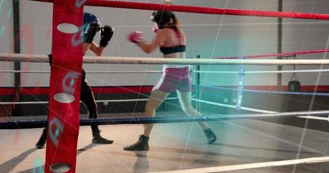 Female boxer in pink shorts advancing during intense sparring match inside boxing ring
