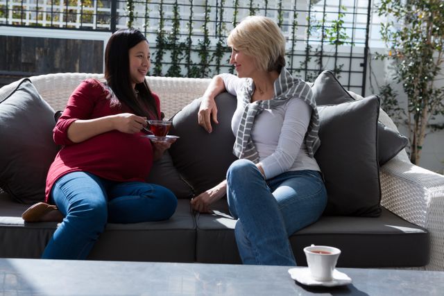 Female friends interacting with each other while having lemon tea in living room