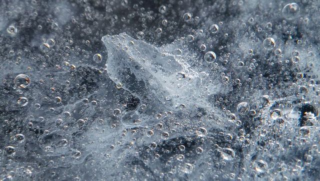 Macro frozen pond ice revealing trapped air bubbles, crystal textures and iridescent hues
