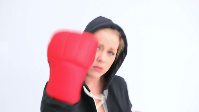 Dynamic image of a woman boxing with intense focus, showing the power and action involved in a workout. Perfect for portraying themes of fitness motivation, female empowerment, self-defense, or sports training programs.