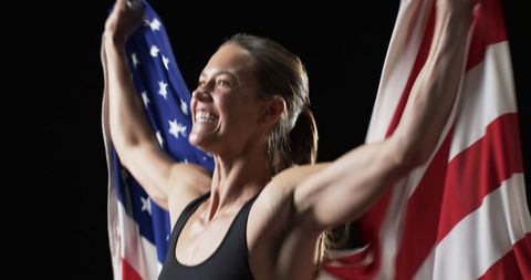 Triumphant athlete celebrating victory holding american flag