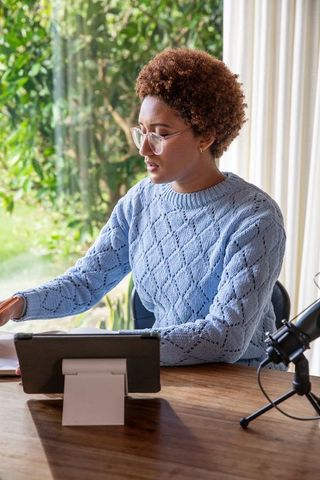 Focused professional using tablet and microphone in modern workspace