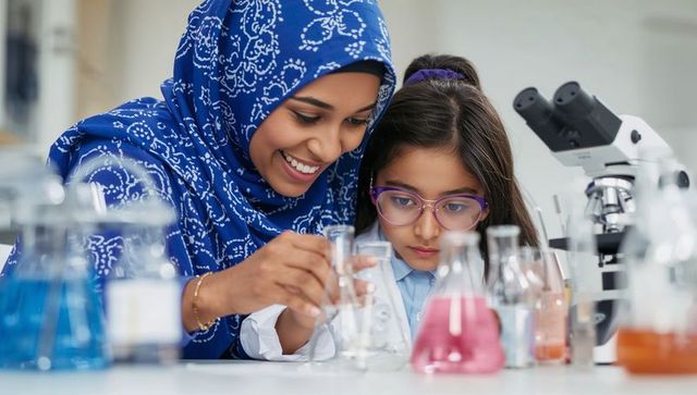 Muslim woman in blue hijab teaching young girl mixing colorful liquids, guiding stem discovery