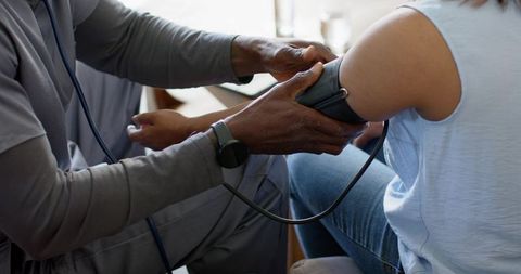Healthcare professional measuring blood pressure on patient arm with stethoscope and cuff