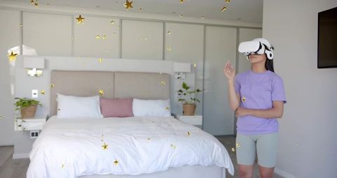 Woman wearing vr headset reaching toward floating gold stars in modern minimalist bedroom