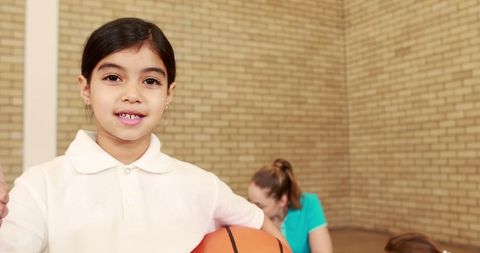Smiling Young Girl Holding Basketball Ready for Game