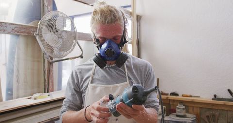 Surfboard Craftsman Checking Tool in Workshop Setting