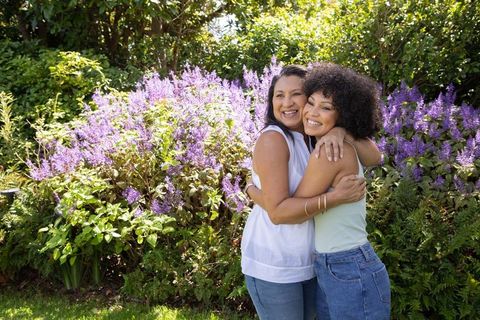 Mother and Daughter Embracing in Garden Amidst Blooming Flowers