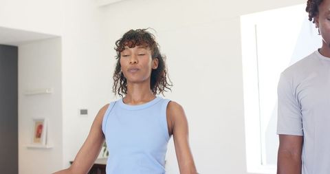 Couple meditating practicing mindfulness and deep breathing in modern minimal living room