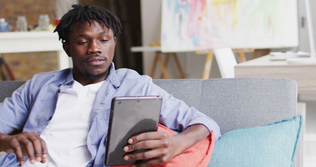 Young Man Browsing Tablet at Home in Modern Living Room - Download Free Stock Images Pikwizard.com