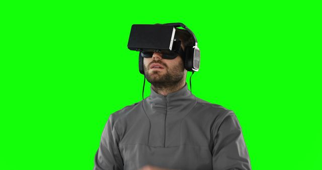 Man wearing a virtual reality headset on a green screen background. Ideal for tech-related content, VR experiences, gaming, digital interfaces, and immersive technology demonstrations. The green screen allows for easy background removal and customization for videos, presentations, and multimedia productions.