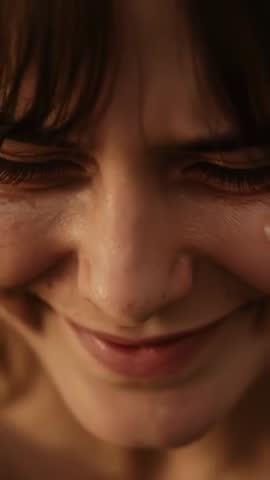 Vertical close-up showing woman holding back tears, eyes closed, tear rolling down cheek