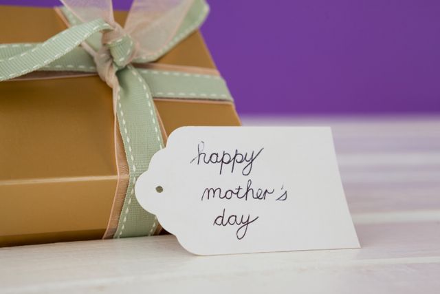 Happy mothers day card with gift box on wooden surface