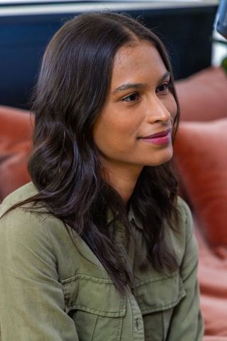 African american woman podcast host sitting on leather couch with boom arm and microphone