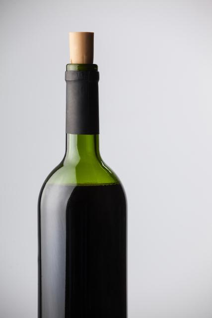 Close-up of red wine bottle against white background